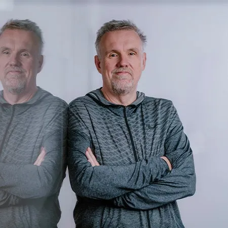 Ein Mann, der vor einem grauen Hintergrund steht.